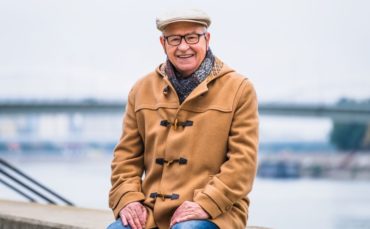 John sitting on a concrete slab by a river.