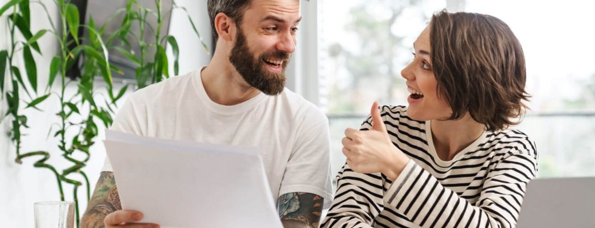 Young couple smiling at each other while reviewing their finances.