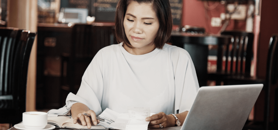 Young woman reviewing her bills using a calculator.